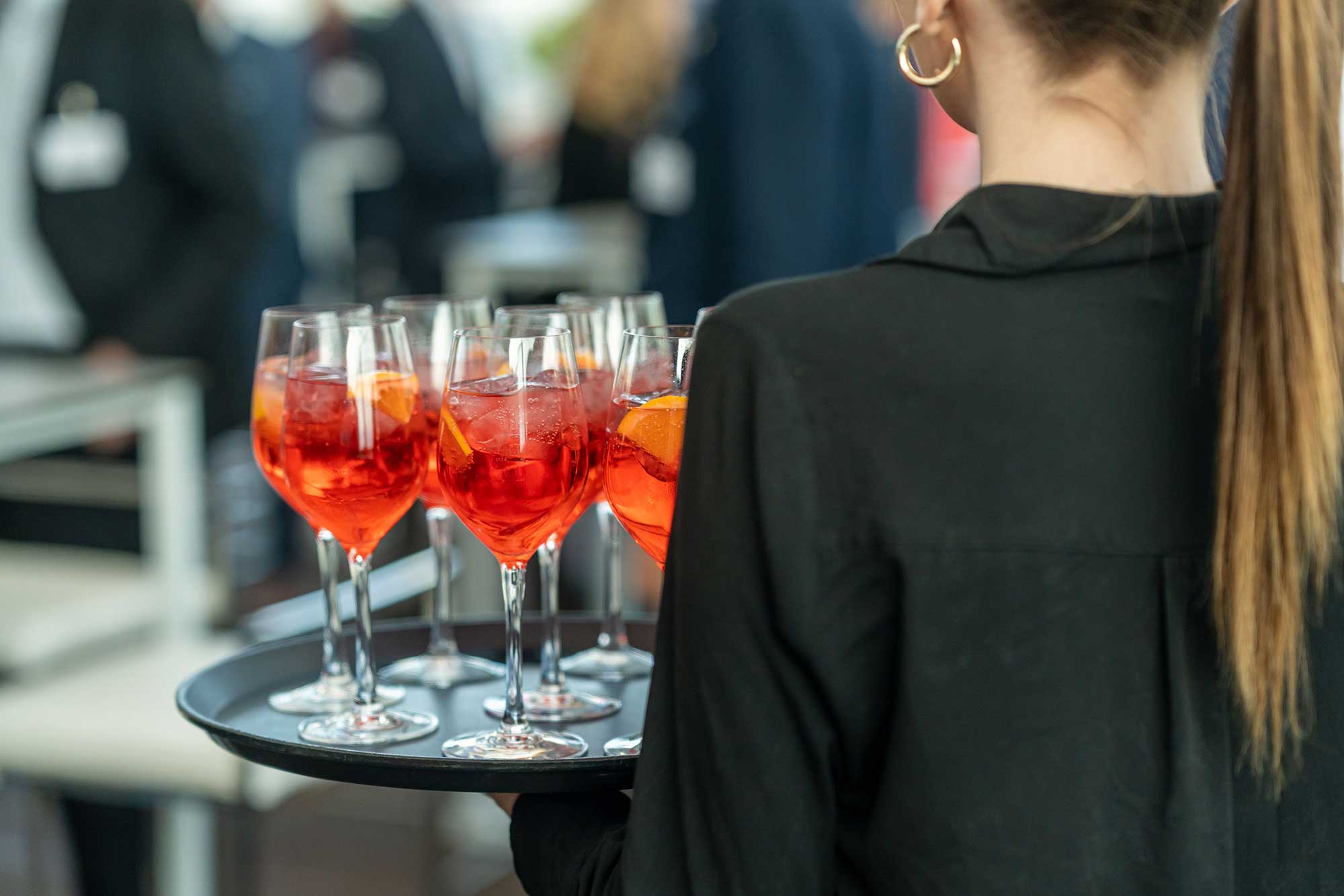 waiter-holding-a-tray-of-aperol-cocktails